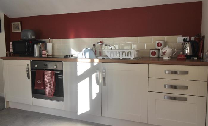 Kitchen area with oven, microwave, toaster, fridge and kettle